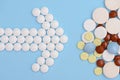 Arrow of white pills and stack of tablets on a blue background