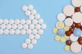 Arrow of white pills and stack of tablets on a blue background Royalty Free Stock Photo