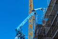 Arrows of blue and yellow construction cranes on the background of scaffolding Royalty Free Stock Photo