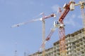Arrows of three cranes above a concrete monolithic building under construction Royalty Free Stock Photo