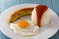 Arroz a la cubana Typical Cuban rice with fried banana and fried egg on a plate on wood Royalty Free Stock Photo