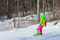 Arsenyev, Russia, January, 28, 2017. Young woman in bright sports clothes snowboarding near town of Arsenyev in Primorsky Krai