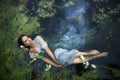 Art beautiful romantic woman lies in swamp in blue long dress with flowers. Portrait brunette in transparent dress in water swamp Royalty Free Stock Photo