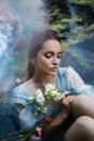 Art beautiful romantic woman lies in swamp in blue long dress with flowers. Portrait brunette in transparent dress in water swamp Royalty Free Stock Photo