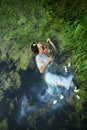 Art beautiful romantic woman lies in swamp in blue long dress with flowers. Portrait brunette in transparent dress in water swamp Royalty Free Stock Photo