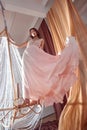 Art beauty woman in long beige pink dress dances and spins on large crystal chandelier in center of hall. Fantasy Fashion woman in Royalty Free Stock Photo