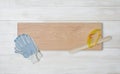 Art composition featuring of gloves, glasses, centimeter ruler and beige wooden plank lying on white workbench Royalty Free Stock Photo