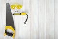Art composition featuring of saw, glasses and centimeter ruler lying on white wooden surface Royalty Free Stock Photo