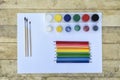 Art concept. Colored pencils, brushes and jars of paint on a blank sheet of paper. Wooden table Royalty Free Stock Photo