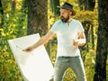 Art concept. Painting in nature. Start new picture. Painter with easel and canvas. Bearded man painter looking for Royalty Free Stock Photo