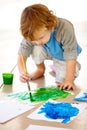 Art, creative and a messy boy painting paper on the floor of his bedroom at home for school homework. Learning, growth