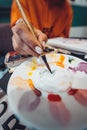 Close up of artist with palette, paint brush and easel painting at studio Royalty Free Stock Photo