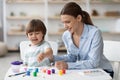 Art development at home. Happy little boy painting with young beautiful mother and laughing, enjoying pastime together Royalty Free Stock Photo