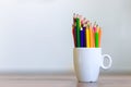 Stack of colored pencils in a glass on wooden background Royalty Free Stock Photo