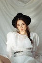 Art fashion portrait of a young beautiful elegant blrunette woman with fashion black hat, natural makeup posing in Royalty Free Stock Photo