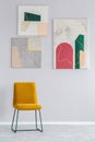 Art on grey wall of fashionable waiting room with yellow chair