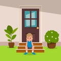 Boy sitting in front of the house looking bored