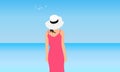 Young woman in coral dress and white hat stands on background of blue sea and sky