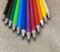 A set of colored wooden pens used for coloring and drawing, stacked horizontally next to each other