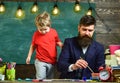 Art lesson concept. Teacher with beard, father teaches little son to draw in classroom, chalkboard on background. Child Royalty Free Stock Photo