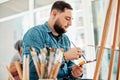 Art is life. a handsome young artist sitting and painting during an art class in the studio. Royalty Free Stock Photo