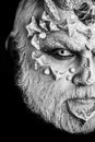 Art make-up. Man with dragon skin and grey beard, half face