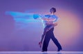 Art in motion. Flexible adorable ballroom dancers in stage attires dancing isolated on purple background in neon mixed Royalty Free Stock Photo