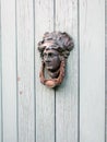 Art Nouveau door knocker of a face on old wood