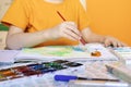 art painting, childrens hands holding brush and drawing of orange paint