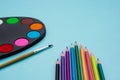 Art palette with paint, brush and colored pencils on blue background Royalty Free Stock Photo