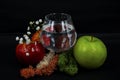 Art photo glass of water red and green apples moss different color white flowers on a black background Royalty Free Stock Photo