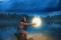 Art photo magic fantasy woman holding moon universe planet ball in hands raises to dark night sky. Mystic witch Girl