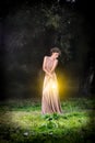 Beautiful girl with brown curly hair in wonderful gold dress tenderness posing with lamps light in fairytale forest. Art photo. Royalty Free Stock Photo