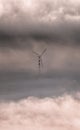 Art photography: wind turbine high among the clouds. Romantic image of a mill in the sky. Metaphor of freedom and flight