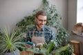 Man wearing apron carefuly looking after plants