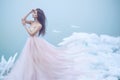 Art portrait of a beautiful young nymph in luxurious strapless ball dress growing into soft clouds