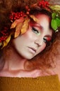 Art portrait of women autumn in her hair, vivid fall colors and makeup, red curly hair and voluminous hair. Leaves and berries