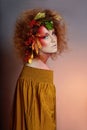 Art portrait of women autumn in her hair, vivid fall colors and makeup, red curly hair and voluminous hair. Leaves and berries