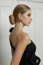 Art portrait of a young blonde woman, hair bun. Beautiful woman in black evening dress. Perfect evening makeup on face, hairstyle