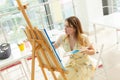 Art school, creativity and leisure concept - student girl or young woman artist with easel, palette and paint brush Royalty Free Stock Photo