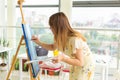 Art school, creativity and leisure concept - student girl or young woman artist with easel, palette and paint brush Royalty Free Stock Photo