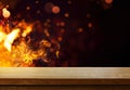 Art Side view of an empty wooden tabletop with orange fire or flames and sparkles on a dark background Royalty Free Stock Photo