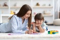 Art therapy for kids. Young woman teacher drawing with cute little boy, interested kid watching at paper on floor Royalty Free Stock Photo