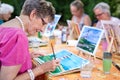 Art therapy for senior ladies, group of women painting the picture of lighthouse from the watercolor template sitting at table.