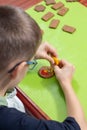 Art work done by a child. A cinnamon round cookie decorated by a child. A smiling face painted with colorful iced felt-tip pens.