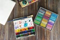 Art workplace, pencils, brushes, watercolor paints, paper and crayon pastel chalks. Flat lay.wooden table