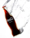 Vertical closeup of the classic Coca-Cola bottle swooshing under water leaving a trail of bubbles.