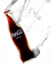 Vertical closeup of the classic Coca-Cola bottle swooshing under water leaving a trail of bubbles. Royalty Free Stock Photo