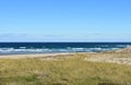 Wild beach with grass, sand dunes and blue sea with waves and foam. Clear sky, sunny day. Galicia, Spain. Royalty Free Stock Photo