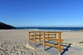 Beach with wooden handrail and morning light. Golden sand and blue sea with waves and white foam. Sunny day, Galicia, Spain. Royalty Free Stock Photo